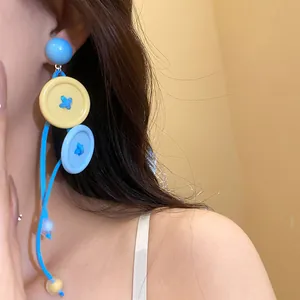 Gros plan de boucles d'oreilles boutons colorées bleu clair et jaune style dopamine.