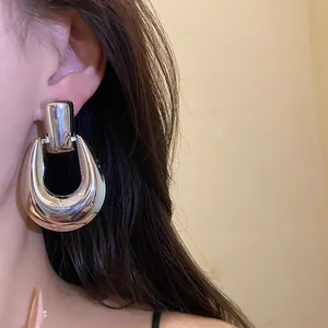 Dettaglio ravvicinato di eleganti orecchini metallici argentati a forma di U indossati sull'orecchio