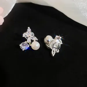 Detail macro view of elegant butterfly zircon and pearl clip-on earrings on black velvet