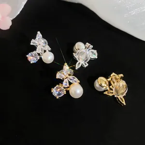 Detailed macro view of 18k gold plated butterfly clip-on earrings with zircon and pearls.