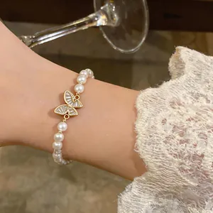 Primo piano del bracciale di perle placcato oro 18k con ciondolo a farfalla