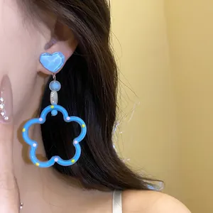 Gros plan détaillé de boucles d'oreilles pendantes cœur et fleur bleu bonbon d'été