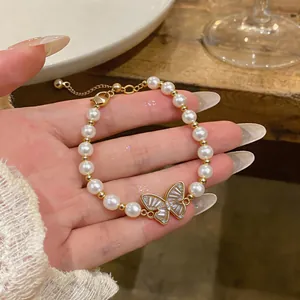 Dettaglio di un elegante braccialetto di perle con ciondolo a farfalla placcato in oro 18 carati