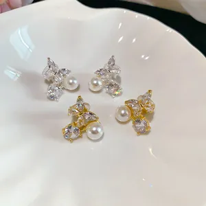 Detailed view of butterfly-shaped ear clips with zircons and pearls