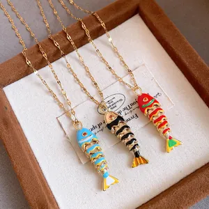 Detailed view of three enamel fish pendants in red, black, and blue on gold chains.