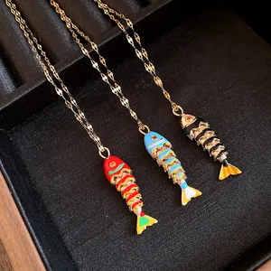 Detailed view of three colorful enamel fish pendants on gold stainless steel chains.