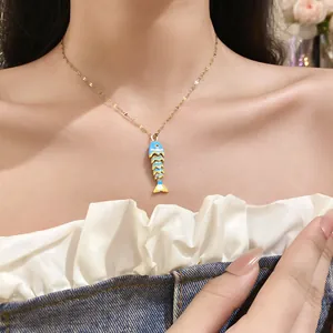 Detail of blue and yellow enamel fish pendant on a dainty gold stainless steel chain.