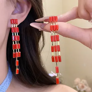Close-up of retro palace style earrings with red rectangular pendants and gold bars