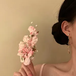 Close-up of pink fabric flower hair clip with pearls and green beads