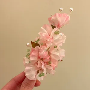 Close-up detail of pink fabric flower hair clip with elegant pearls and green beads accessory