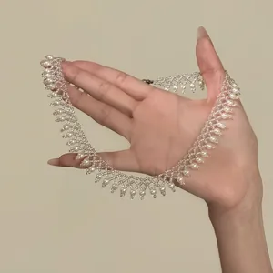 Detailed view of a French design pearl and glass bead necklace held in hand to show scale