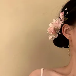 Close-up of pink fabric flower hair clip with pearls worn on side of head