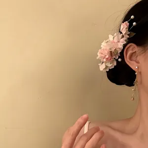 Close-up detail of an elegant fabric flower hair clip with pearls on a female model