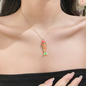 Close-up of colorful enamel fish pendant necklace on model's neck, gold finish.