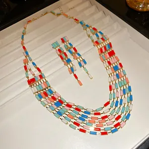 Detail view of a retro multi-strand rectangular patchwork necklace and earring jewelry set on tray