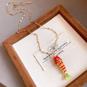 Close-up detail of the colorful enamel fish pendant on a gold stainless steel chain.