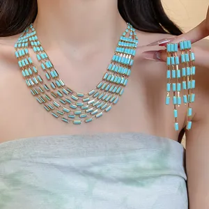 Detail of vintage turquoise rectangle pendant necklace and tassel earrings set on model.