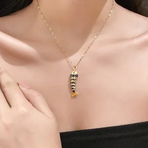 Detailed view of a gold-plated stainless steel fish pendant necklace on a model's neck.