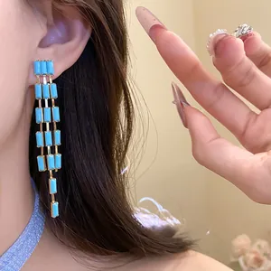 Detail shot of vintage long tassel earrings with blue rectangular stones on model