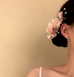 Detailed side view of an elegant pink fabric flower hair clip with pearls on a model's hair