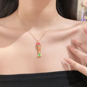 Detailed view of the red and gold fish pendant necklace worn by a model for fashion display
