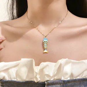 Detailed view of a blue enamel fish bone pendant necklace on an elegant collarbone