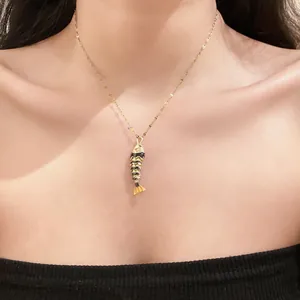 Detailed view of a stylish gold-toned fish pendant necklace with black enamel finish