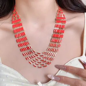 Close-up detail of multi-strand necklace with red rectangular links and gold trim.