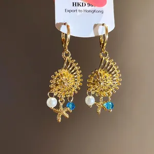 Detalle de pendientes vintage de concha dorada con perlas y colgantes de estrella de mar