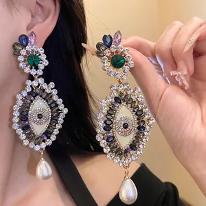 Detail macro view of vintage evil eye earrings with colorful rhinestones and pearl drops.