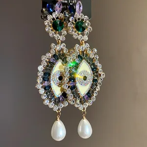 Detailed shot of vintage eye earrings featuring colorful crystals and pearl drops