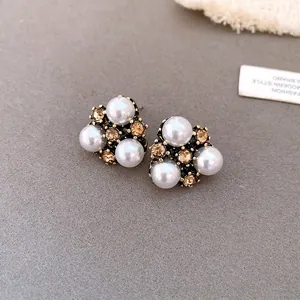 Dettaglio macro di orecchini a perno vintage con perle e cristalli ambrati di lusso.