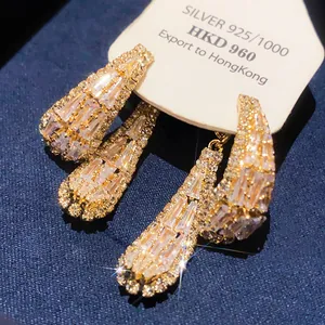 Détail des boucles d'oreilles pendantes à pompons en zircon de style français sur fond bleu
