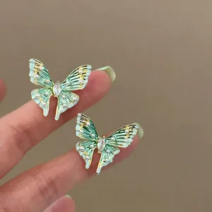 Close-up detail of mint green enamel butterfly earrings featuring pearls and crystals