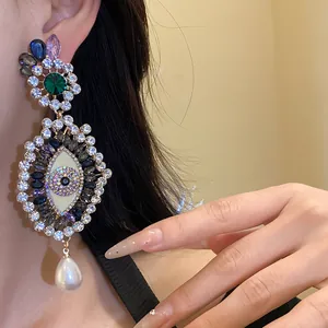 Detail view of a vintage crystal evil eye dangle earring with a large teardrop pearl