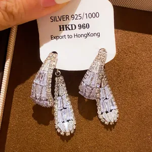 Gros plan sur des boucles d'oreilles de luxe françaises avec zircons étincelants.