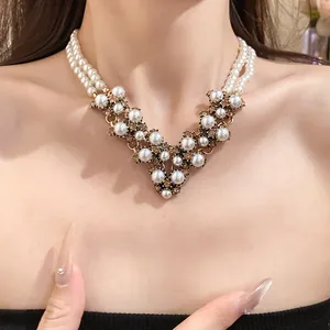 Primo piano di una collana di perle vintage con strass ambrati sul collo di un modello.