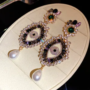 Detailed view of ornate evil eye earrings with sparkling rhinestones and pearls