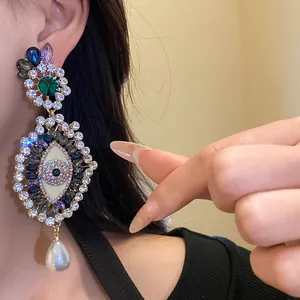Vintage style evil eye drop earrings with shimmering rhinestones and a white teardrop pearl.