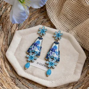 Exquisite vintage floral drop earrings with blue rhinestones and glass pendants on a tray