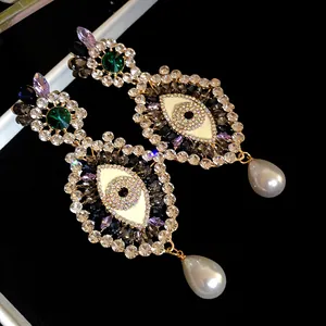 Detail of vintage evil eye earrings with colorful rhinestones and elegant pearl drops.