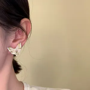 Close-up of an elegant enamel butterfly stud earring with shimmering pearl-like details