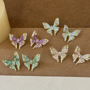 Detailed view of multi-colored enamel butterfly stud earrings with delicate pearls