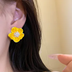 Dettaglio di un orecchino a fiore in smalto giallo con centro in zircone brillante.