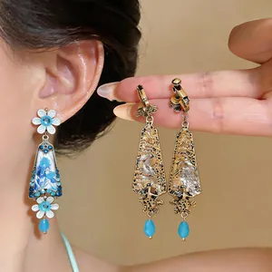 Close-up detail of vintage flower drop earrings with blue rhinestones and gold finish