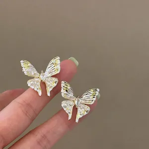 Close-up of elegant enamel butterfly stud earrings with small pearls and crystals.