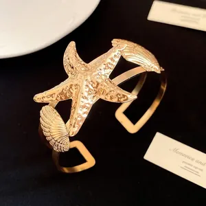 Vintage gold metallic cuff bracelet with textured starfish and seashell design charms