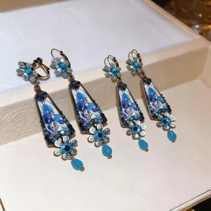 Detailed macro view of vintage blue floral glass pendant earrings with rhinestones