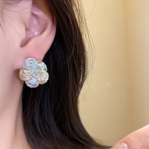 Primo piano dettagliato di un orecchino a fiore testurizzato con zircone sull'orecchio