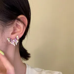 Detail view of elegant purple enamel butterfly earring worn on ear with fine gold accents.